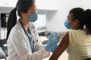 doctors at hospital wearing mask and giving patient injection