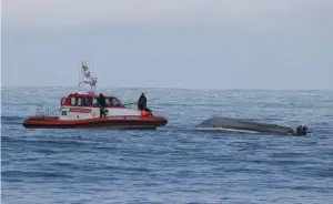 A coastguard boat with the capsized boat off Kaikoura