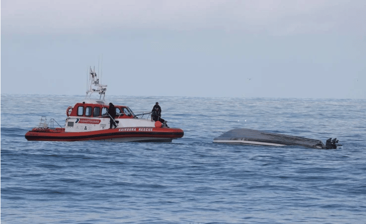 A coastguard boat with the capsized boat off Kaikoura