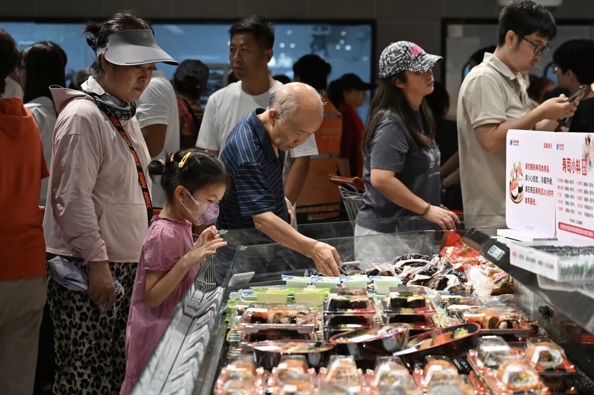 Customers purchase sushi at a supermarket on August 9, 2025 in Beijing, China
