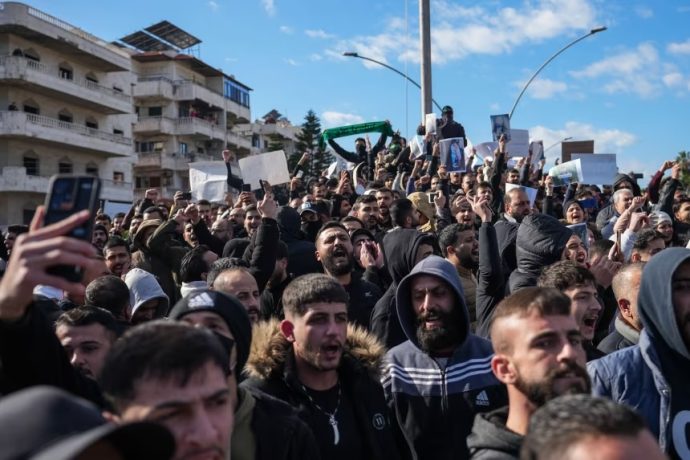 Members of the Alawite community gather on Sunday to protest violence against Alawites following the Homs mosque bombing in the city of Latakia Syria.