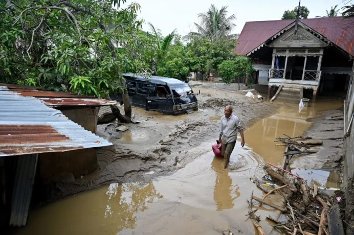A man wades through the floodwaters following flash floods in Meureudu, in Indonesia's Aceh province, on November 28.