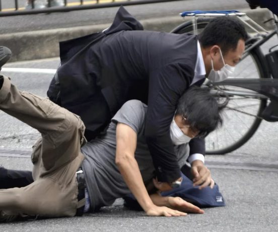 Tetsuya Yamagami, bottom, is detained near the site of the assassination in Nara, western Japan, on July 8, 2022.
