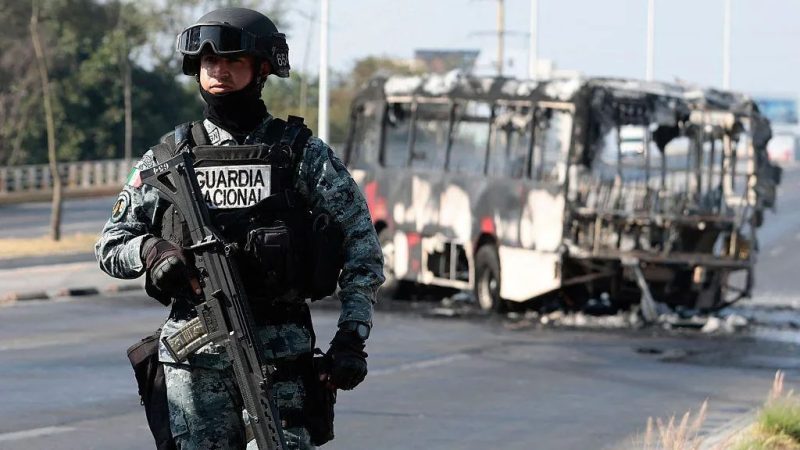 A member of Mexico's National Guard stands near the charred wreckage of a bus that appears to have been set on fire by organised crime groups in Jalisco state on Sunday.