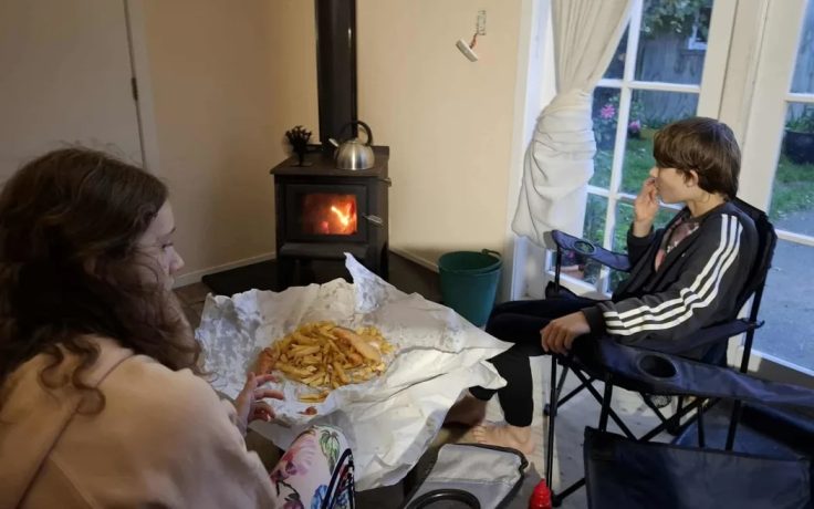 Natasha Eagle's 10 and 12-year-old children after they got the go-ahead from builders to light the fire after several days in the cold in Island Bay.