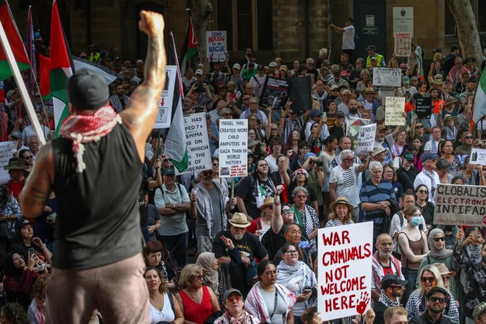 People hold up placards during a protest against the visit of Israel's President Isaac Herzogin Sydney, Australia, on February 09, 2026.