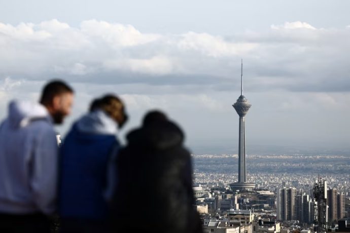 People stand at a park in view of Milad Tower, amid the U.S.-Israeli conflict with Iran, in Tehran, Iran, on March 25, 2026.