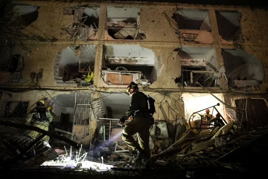An Israeli soldier uses a torch to inspect the damage after Iranian missile barrages struck Dimona, amid the US-Israel conflict with Iran, in southern Israel on Saturday.