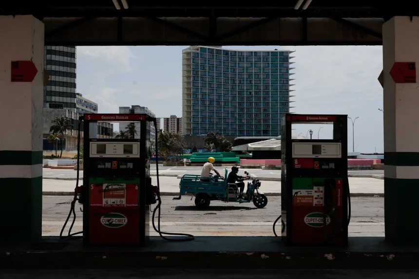 An electric tricycle driver passes in front of a gas station in Havana, Cuba.