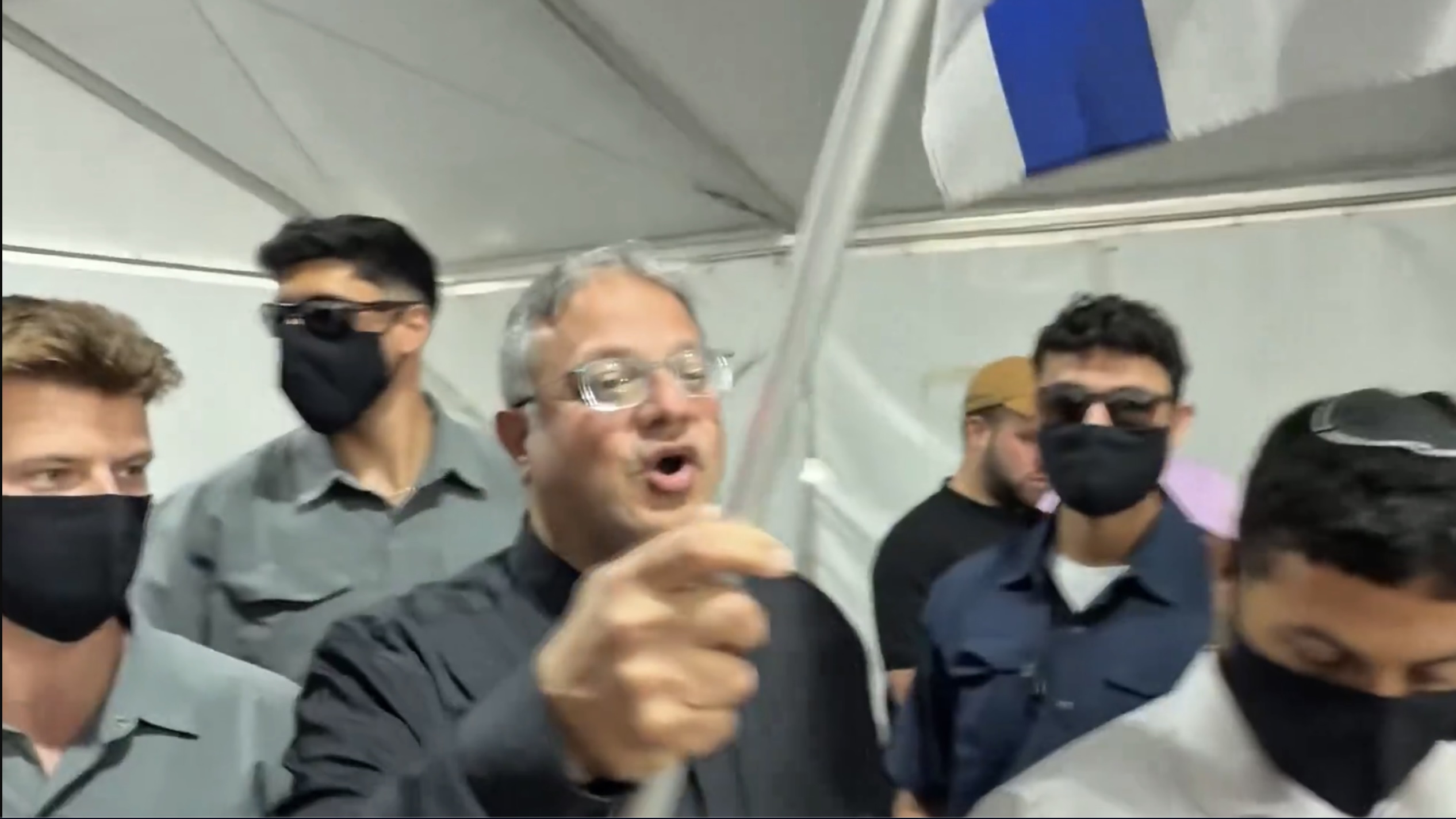 Itamar Ben-Gvir waved an Israeli flag while walking among protesters in handcuffs kneeling on the floor. (X/@itamarbengvir)