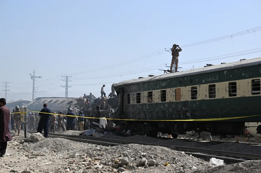 Security personnel inspect damaged derailed carriages.