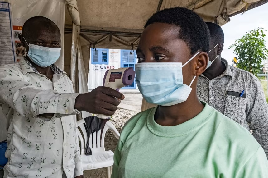 A border health officer at the Busunga crossing between Uganda and the Democratic Republic of Congo checks a traveler's temperature in Bundibugyo, on Monday.
