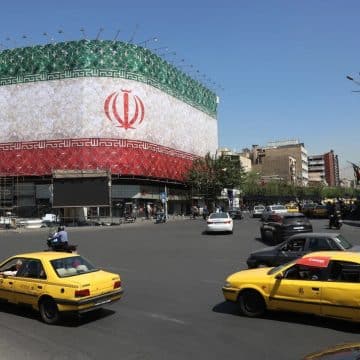 Traffic moves past the Iranian national flag displayed on a building at Enghelab square in Tehran on Sunday.