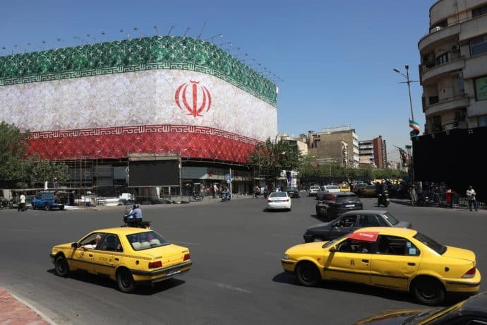 Traffic moves past the Iranian national flag displayed on a building at Enghelab square in Tehran on Sunday.