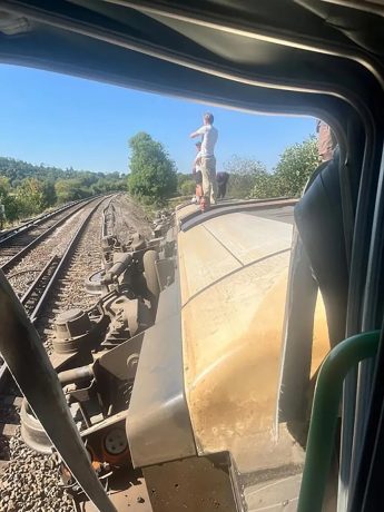 People stand on an overturned train carriage after the derailment in Lewes on Thursday afternoon.