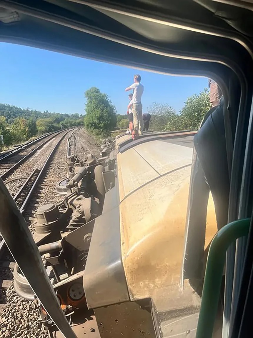 People stand on an overturned train carriage after the derailment in Lewes on Thursday afternoon.